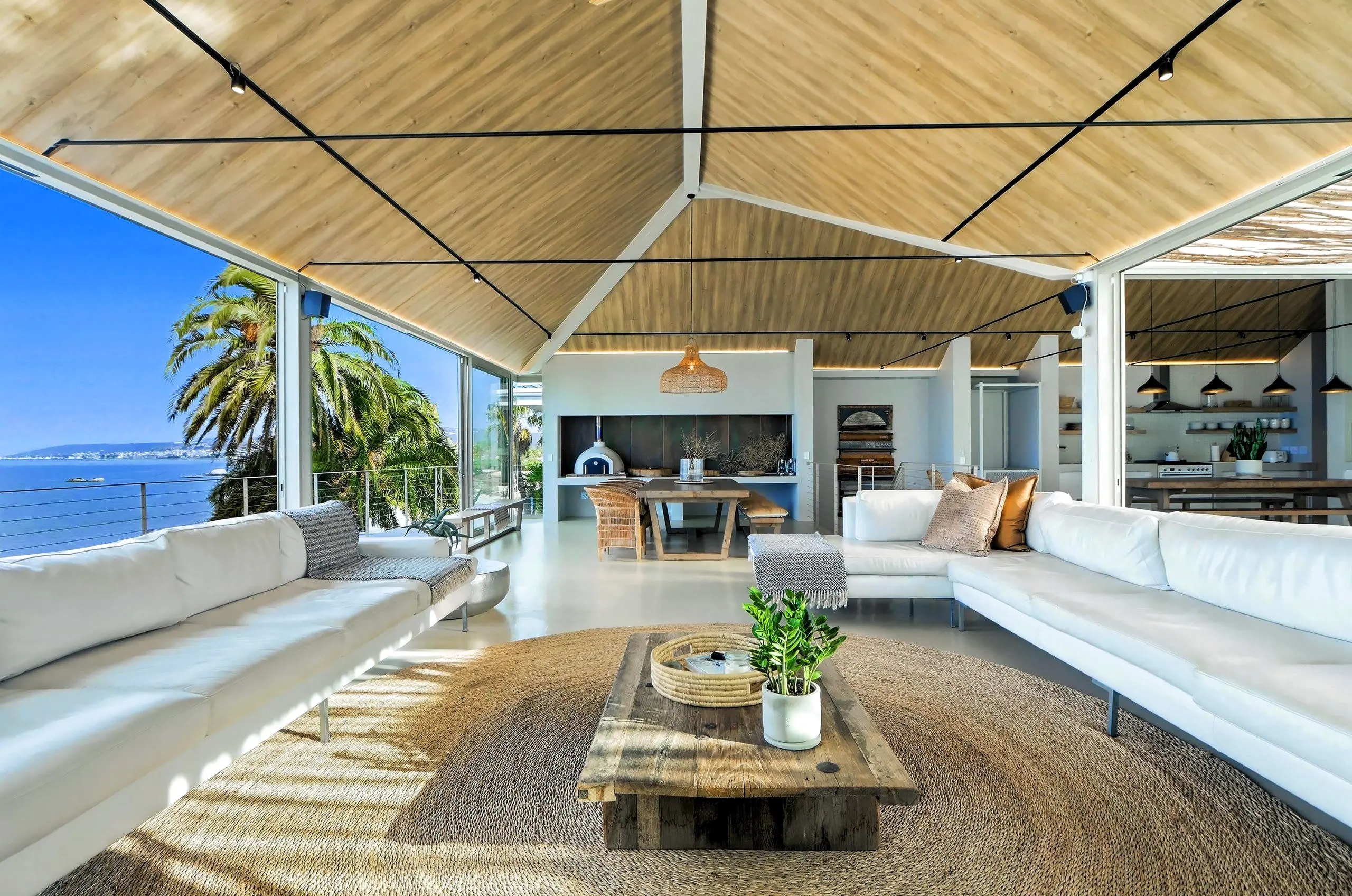 Lounge looking towards the dining table, pizza oven and open kitchen under the timber ceiling