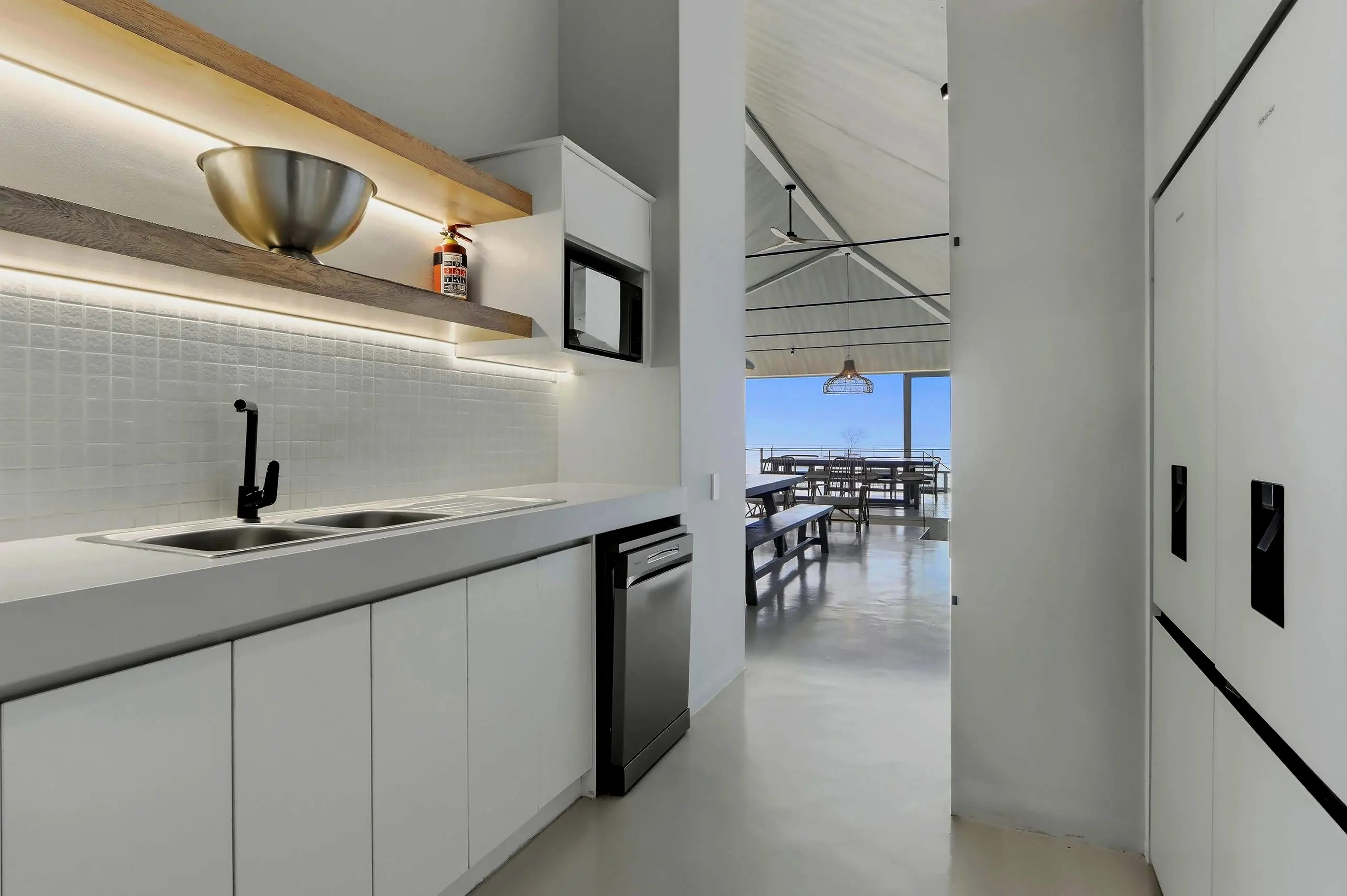 Scullery with double sink, dishwasher and two fridge-freezers, looking through to the dining floor