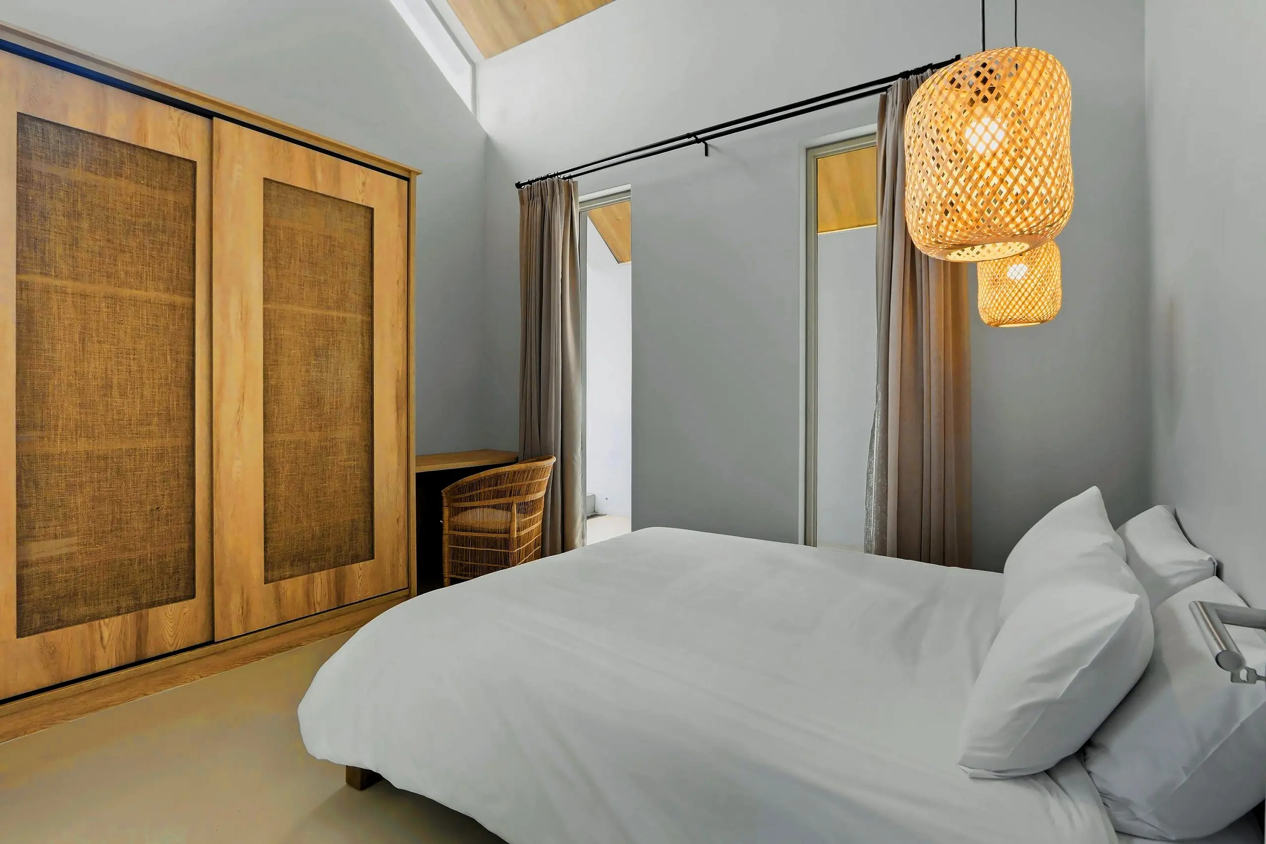 Loft bedroom under the timber ceiling with wardrobes, a desk and bamboo pendants
