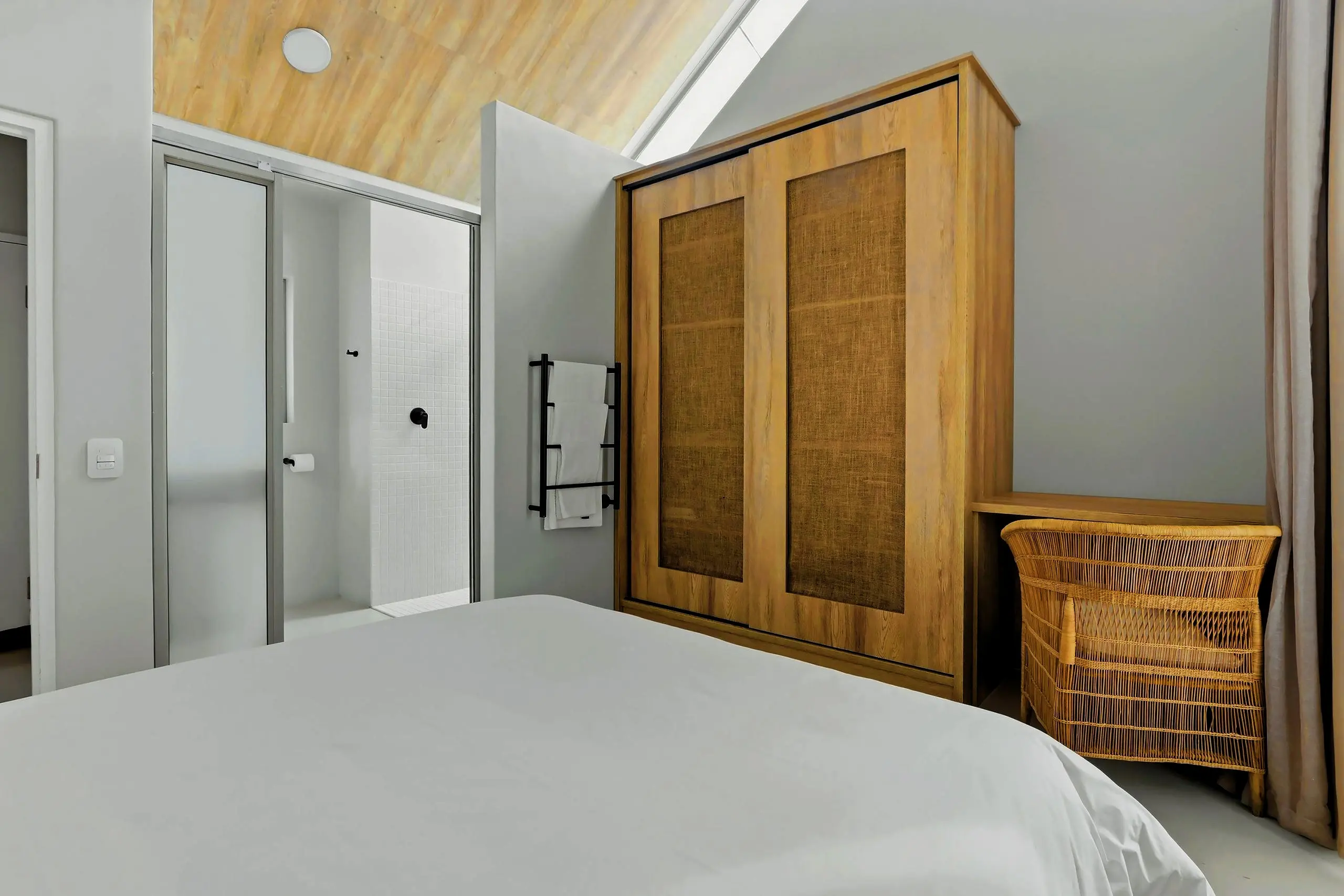 Loft bedroom with a sliding wardrobe, rattan stool and mirrored door to the en-suite