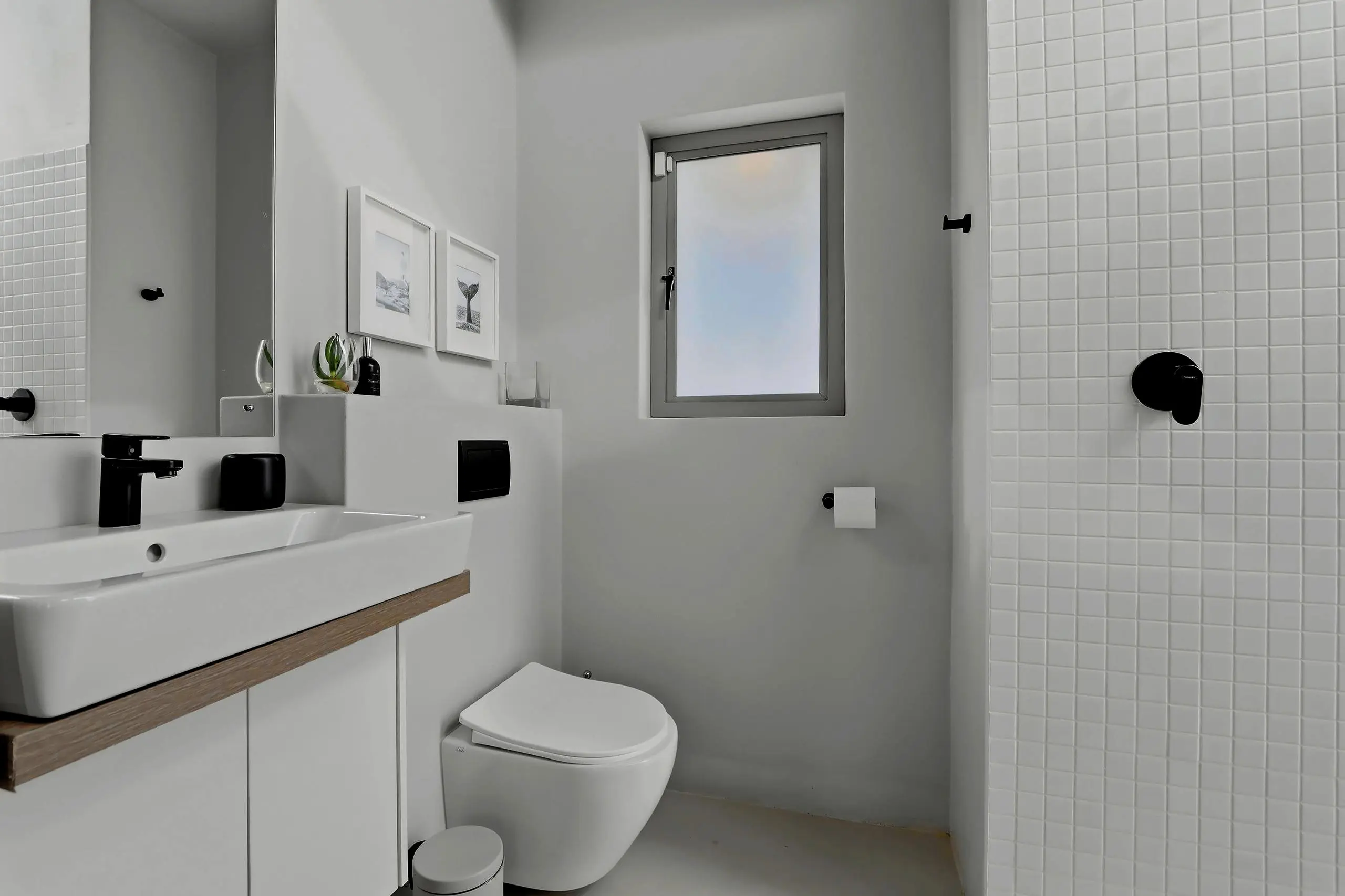 Small bathroom with basin, wall-hung toilet and framed prints