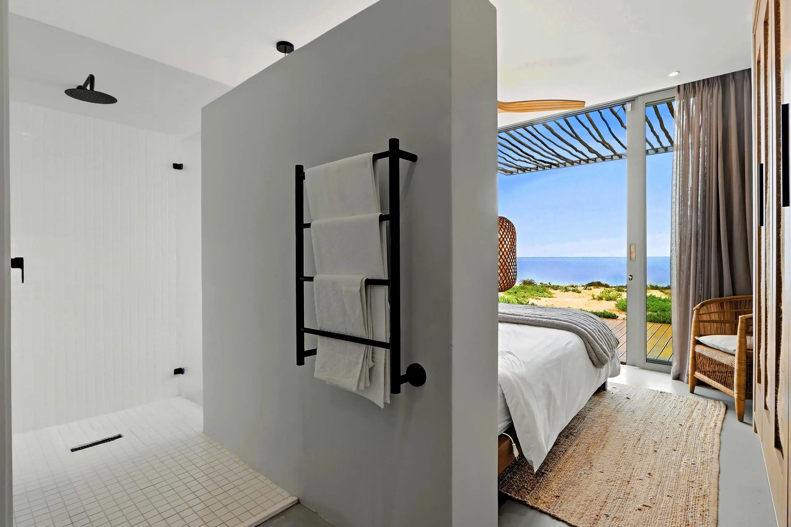 Walk-in shower with heated towel rail beside the bedroom opening to the sea