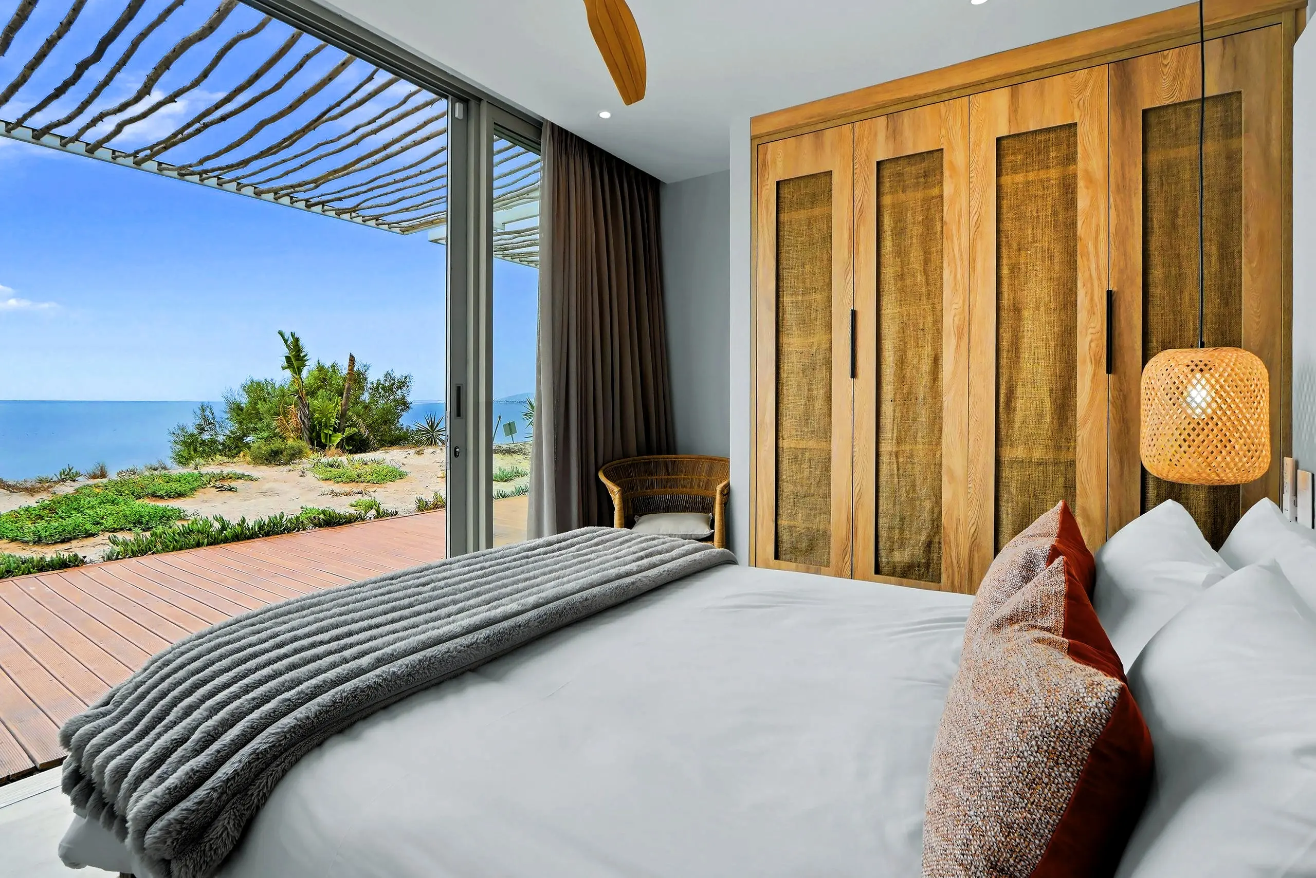 Sea-facing bedroom with an extra-length bed, timber wardrobes and sliding glass to the deck and dunes
