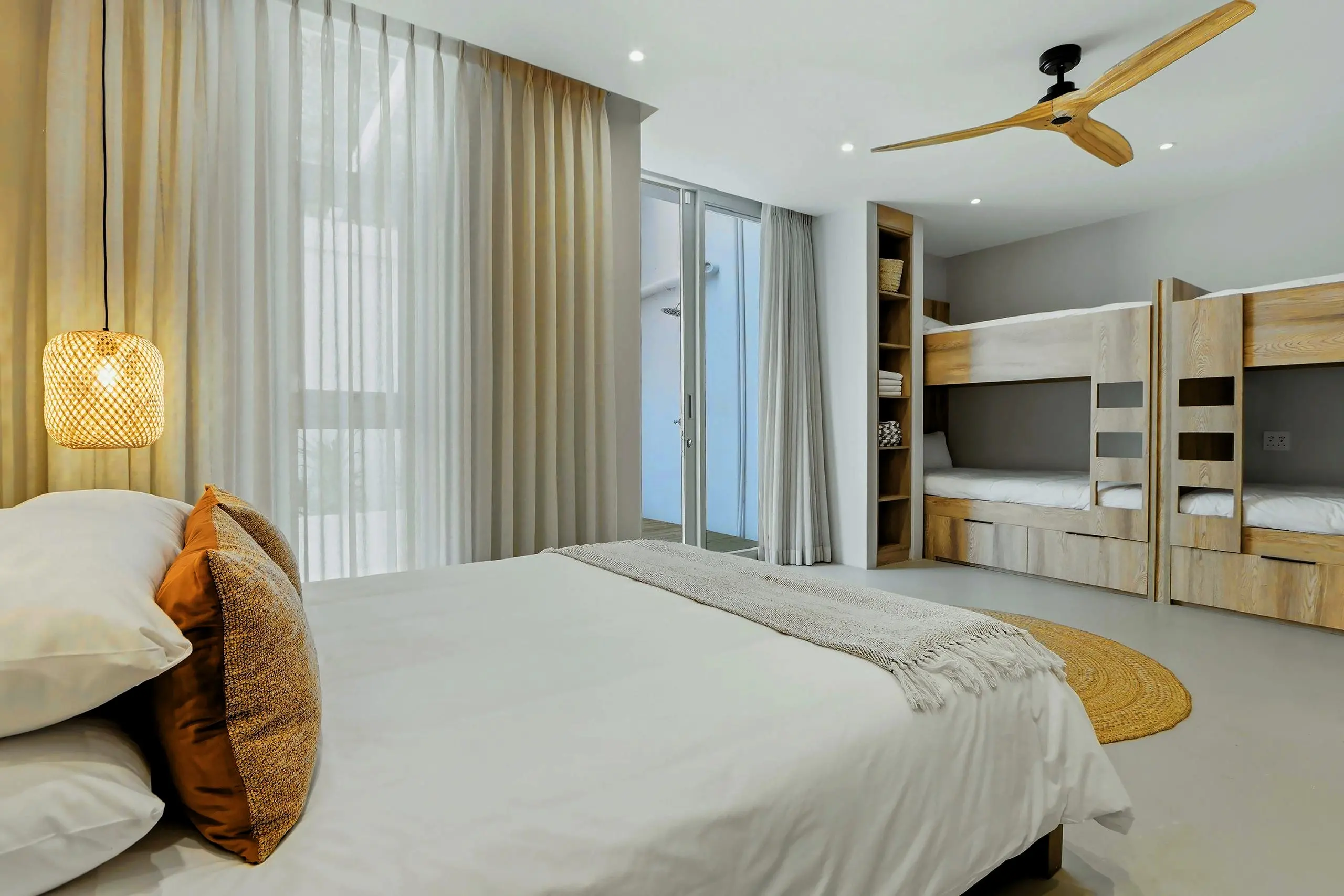 Family room with a double bed, sheer curtains and four built-in timber bunk beds
