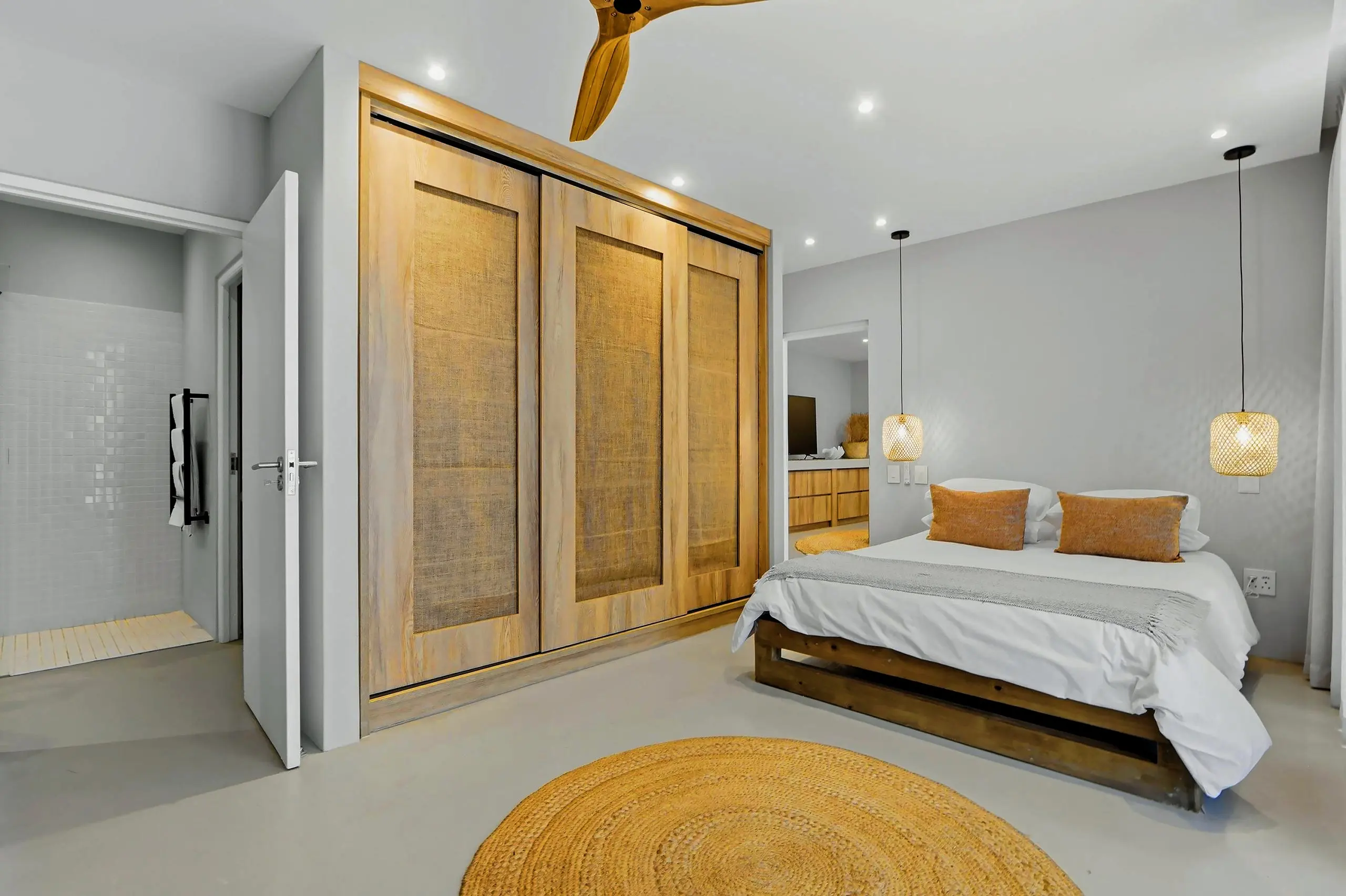 Bedroom with triple hessian-panelled wardrobes, a jute rug and a door to the shower room
