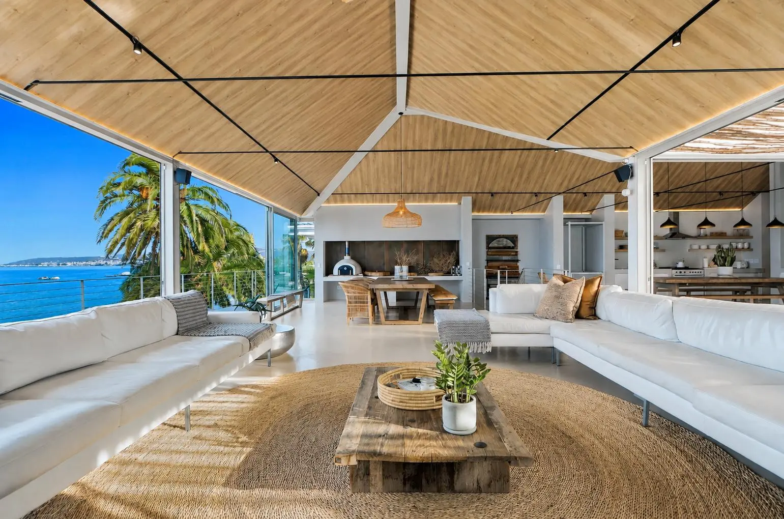 Upper-floor lounge under a timber vaulted ceiling, open on two sides to palms and St Helena Bay