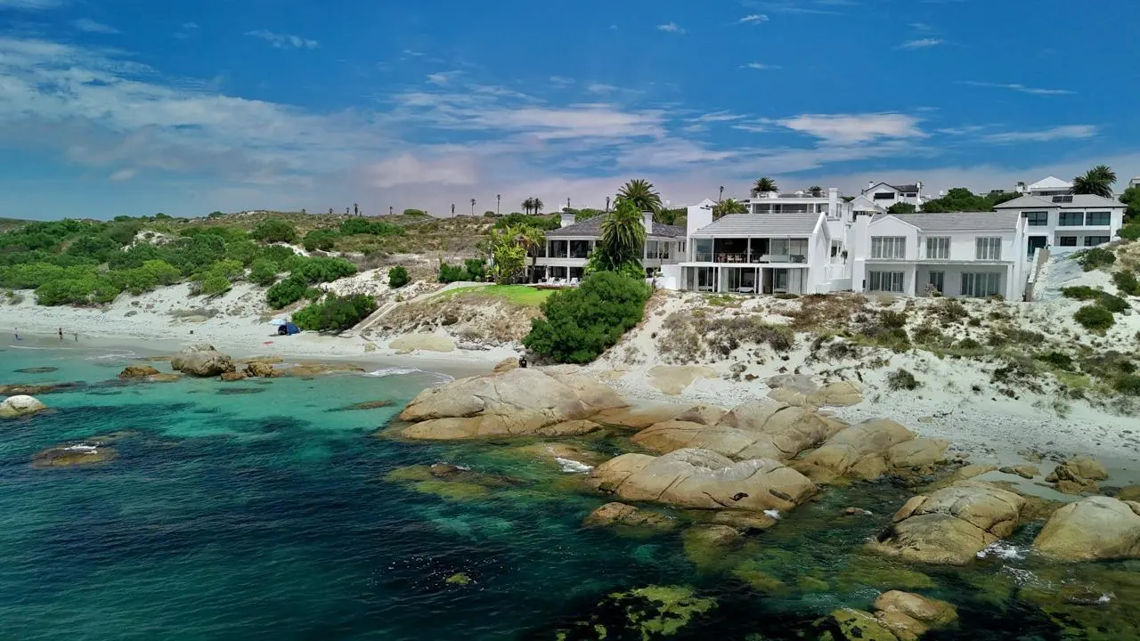 Villa Selah from over the water: the white villa on the dune above granite boulders and the turquoise shallows of the bay
